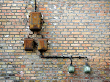 Rusty fuse boxes on brick wall