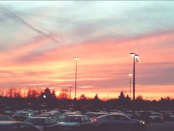 Cars on road against cloudy sky at sunset