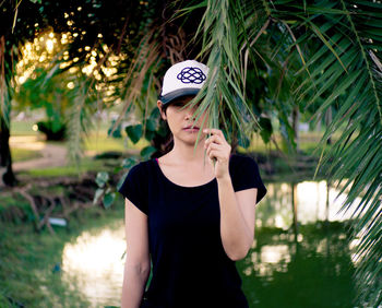 Young woman looking away while standing against plants