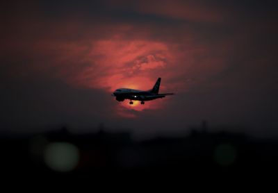 Airplane flying in sky at sunset