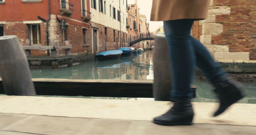 Low section of man standing by canal in city