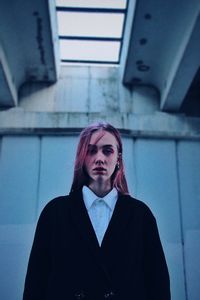 Portrait of young woman standing against wall