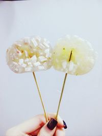 Close-up of hand holding ice cream over white background