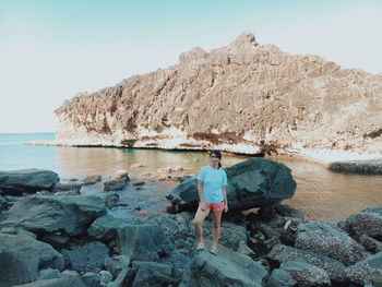 Rear view of man looking at sea shore against clear sky