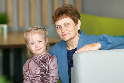 Portrait of smiling grandmother with granddaughter at home