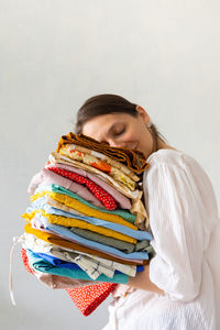 A european woman holds holding a stack of clothes in a wardrobe or boutique.  laundry or recycling