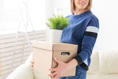 Midsection of woman carrying boxes at home