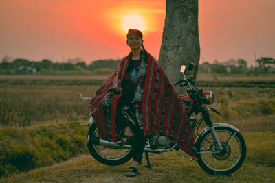 Bicycle on land against sky during sunset