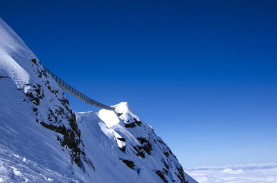 Low angle view of snowcapped mountain against blue sky