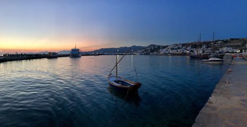 Sailboats moored in river against sky during sunset