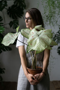 Beautiful woman standing by potted plant