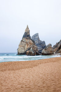 Rock formations on beach against clear sky