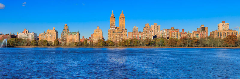 Buildings by sea against clear blue sky