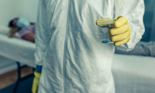 Midsection of man holding umbrella standing in kitchen