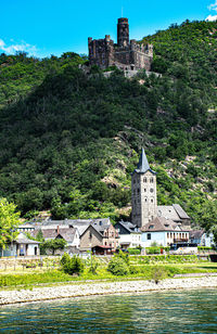 Buildings by river against mountain