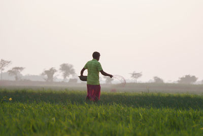 Rear view of man standing on field against sky