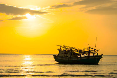 Silhouette boat in sea against orange sky