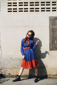 Portrait of woman standing against wall in city