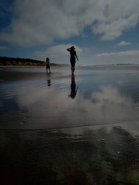 Silhouette people on beach against sky