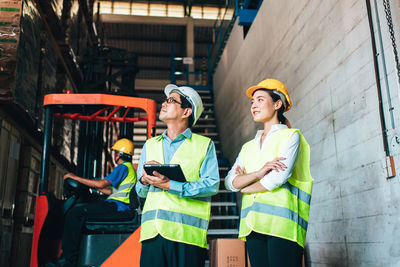 Engineers with arms crossed looking away while standing in factory