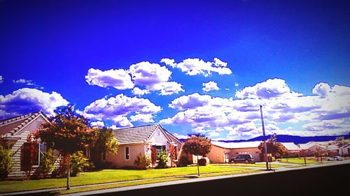 View of houses and trees against blue sky