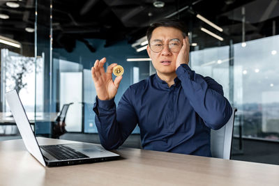 Young man using mobile phone while sitting on table