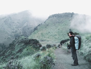 Side view of young man standing on mountain