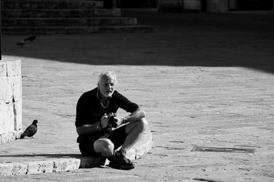 Full length of young man sitting outdoors