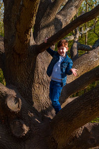 Full length of boy climbing on tree trunk