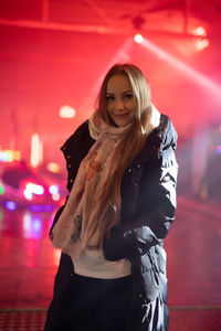 Young woman standing against red wall