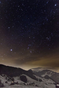 Scenic view of snowcapped mountains against sky at night