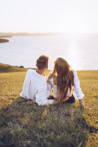 Couple sitting on land against sky