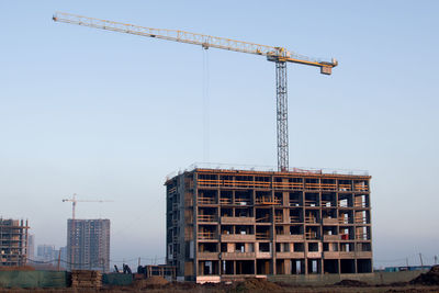 Crane by building against clear sky