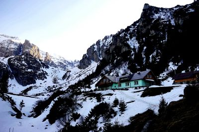 Houses by snow covered mountains against sky