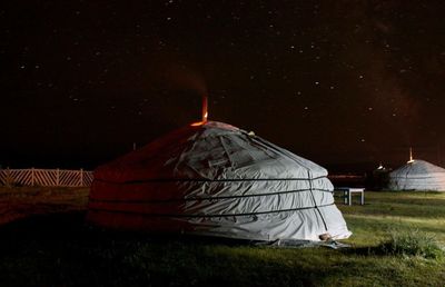 Huts on grassy field against sky at night