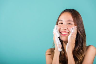 Portrait of young woman against blue background