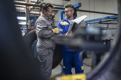 Two tire repairmen with clipboard talking