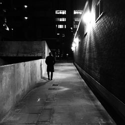 Rear view of woman walking on illuminated street at night