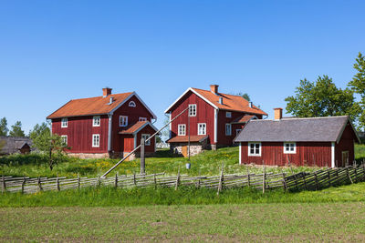 Houses and trees on field against clear sky