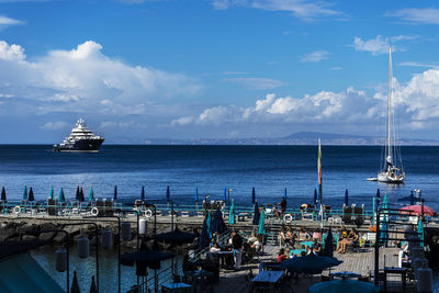 Sailboats moored in sea against sky