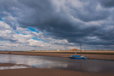 Boat moored on beach against sky