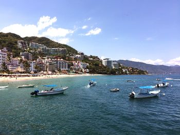 Boats in sea by city against sky