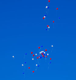 Low angle view of balloons flying against blue sky