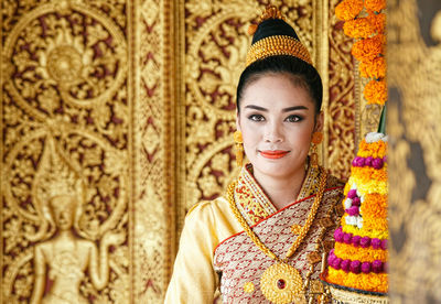 Portrait of smiling young woman wearing traditional clothing standing in temple