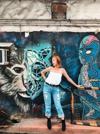 Full length of woman standing against graffiti wall