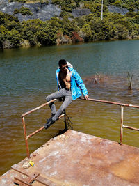 Side view of man sitting on pier over lake