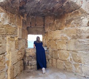 Rear view of woman standing against rock