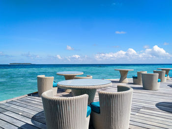 Deck chairs on beach against blue sky