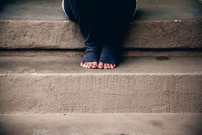 Low section of woman with bare feet sitting on steps