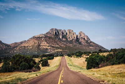 Road by mountains against sky